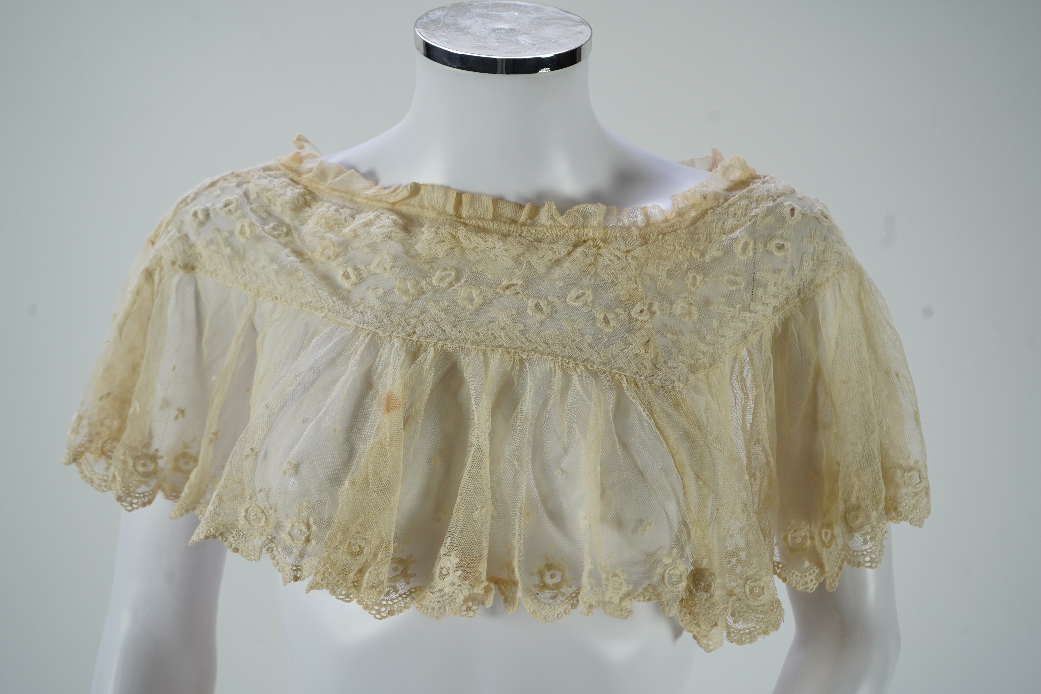 A suitcase containing a cream silk lace skirt to a dress, an Edwardian silk petticoat and various collars, possibly for theatrical use, silk petticoat 96 cm long. Condition - fair